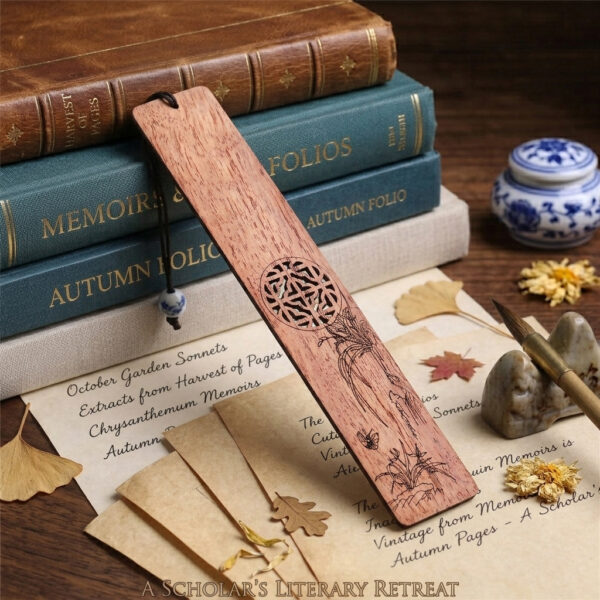 Natural wood orchid bookmark leaned against classic leather books surrounded by calligraphy paper and ginkgo leaves.